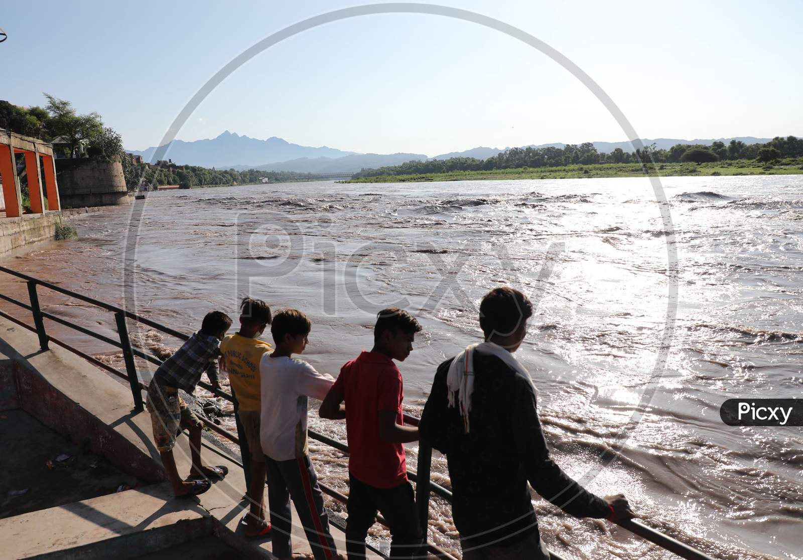 People watching river Chenab in full spate in Akhnoor area of Jammu on August 22, 2020 after authorities opened Salal Dam reservoir gates following heavy rains over the past two days in Jammu and Kashmir.
