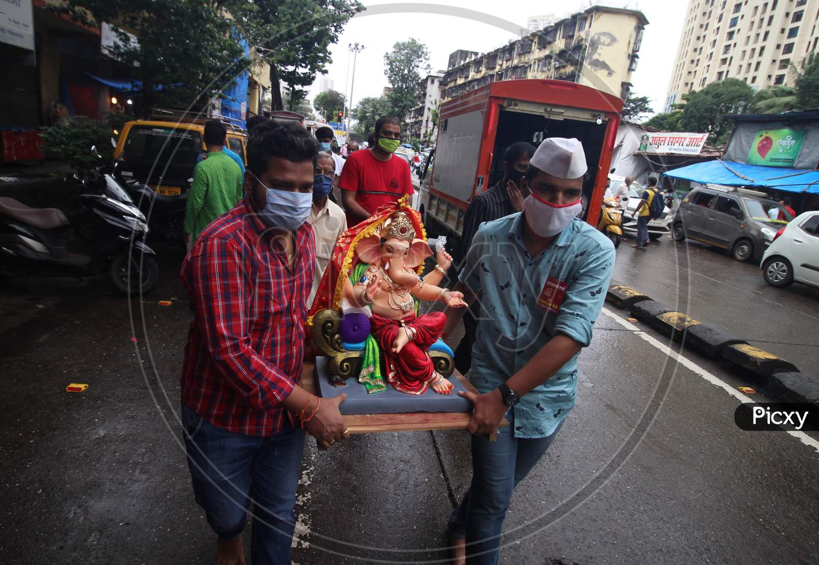 Devotees wearing masks carry home an idol of elephant-headed Hindu god Ganesha for worship during Ganesh Chaturthi festival celebrations in Mumbai, India, on August 22, 2020.