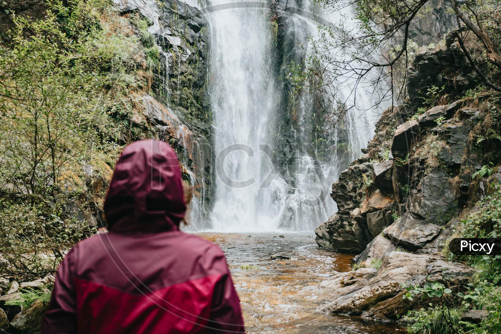 Young Female Hiker In Front Of A Waterfall With Copy Space