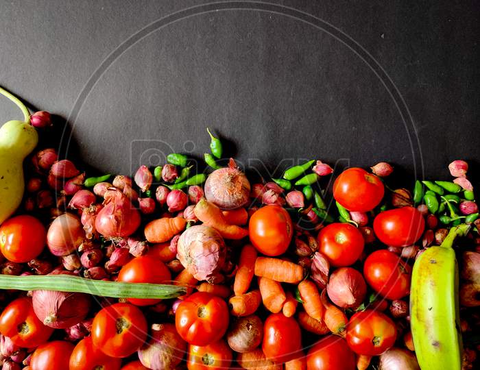 Vegetables Like Tomatoes,Onions,Green Chillies,Carrots,Drumsticks Isolated On Black Background. Copy Space