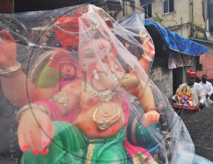 A devotee wearing a mask carries home an idol of elephant-headed Hindu god Ganesha for worship during Ganesh Chaturthi festival celebrations in Mumbai, India, on August 22, 2020.