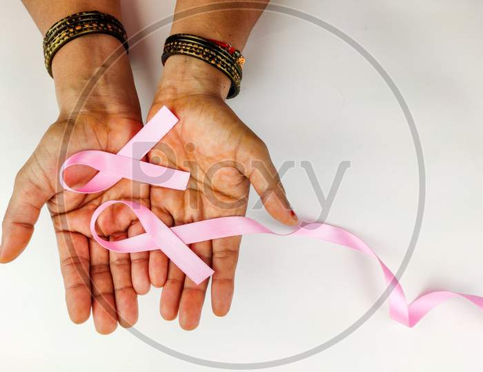 Pink Ribbon In Hand Of Woman , Symbolising Breast Cancer Awareness On White Background, Selective Focus.