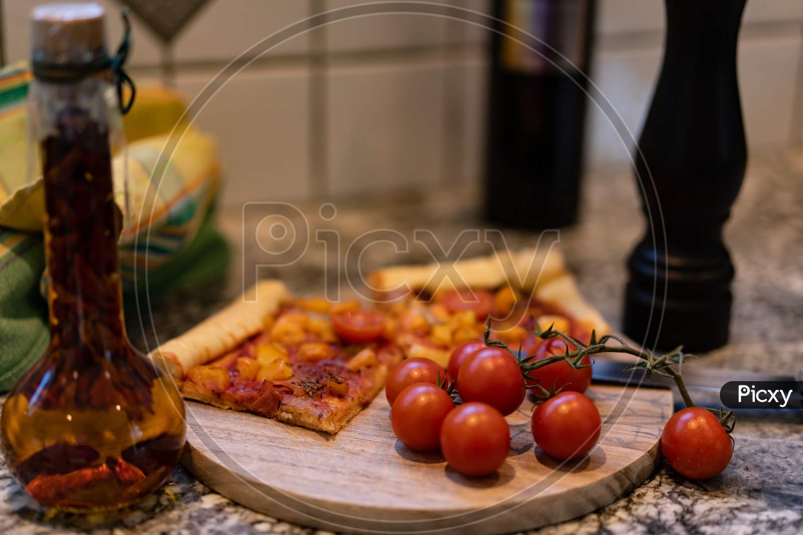 Pizza On A Cutting Board With Fresh Tomatos And Oil And Pepper Mill.
