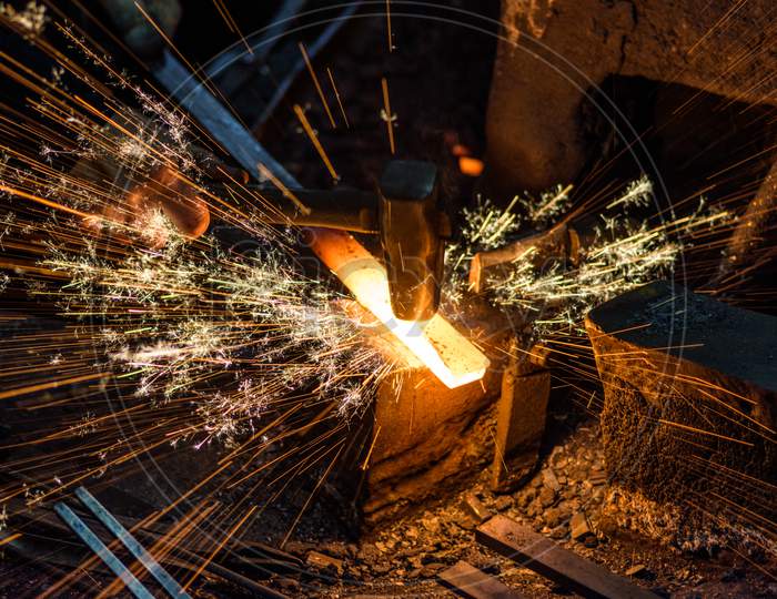 Blacksmith Forging The Molten Metal On The Anvil With Spark Fireworks