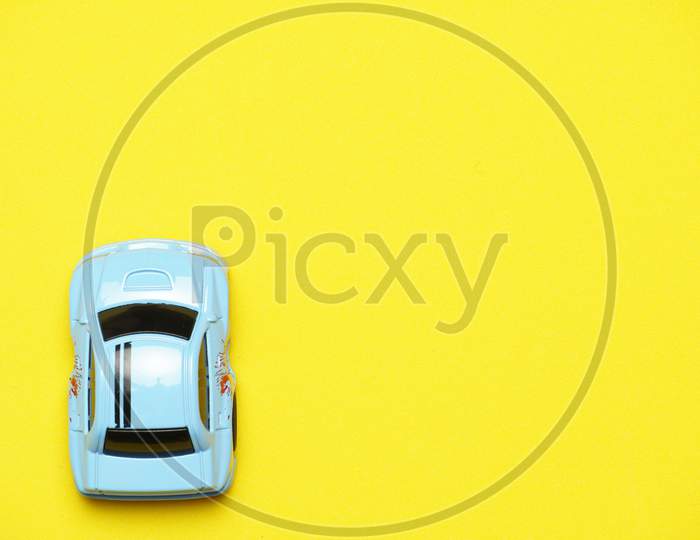 Toy Car On Yellow Background With Copy Space. Flat Lay .Flat Design. Concept Of Traveling By Car