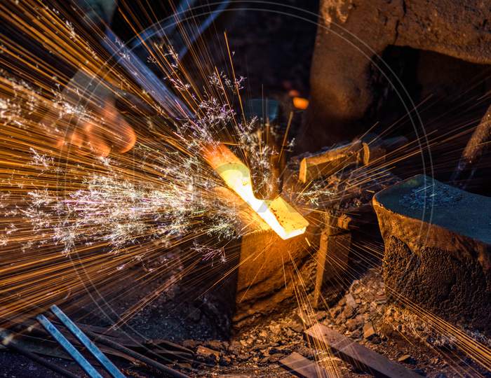 Blacksmith Forging The Molten Metal On The Anvil With Spark Fireworks