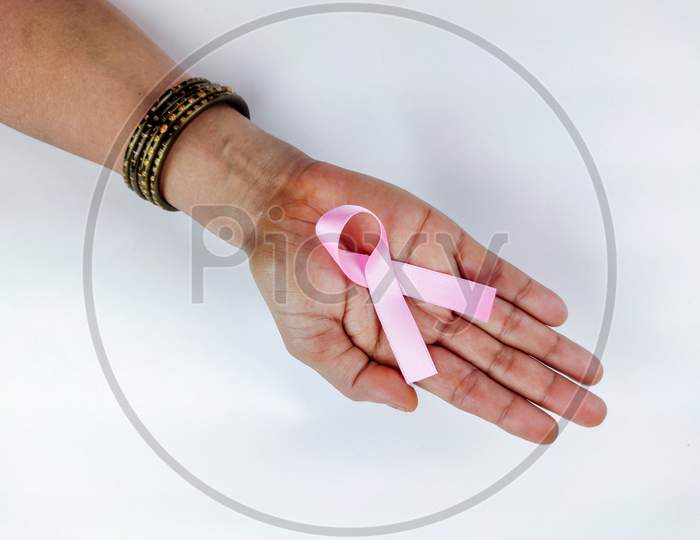 Pink Ribbon In Hand Of Woman , Symbolising Breast Cancer Awareness On White Background, Selective Focus.