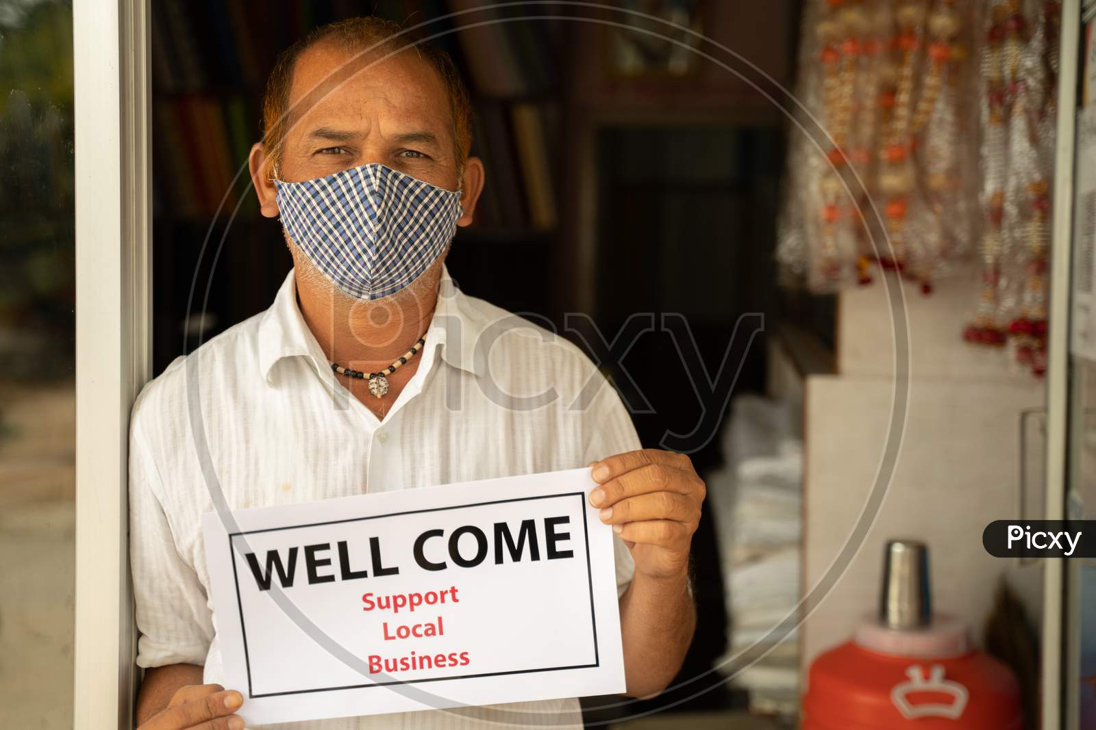 Small Business Owner In Medical Mask Holding Well come Notice In front Of Door After Store Reopening During Coronavirus Or Covid-19 - Concept Of Support Local Business And Restart Work After Pandemic.