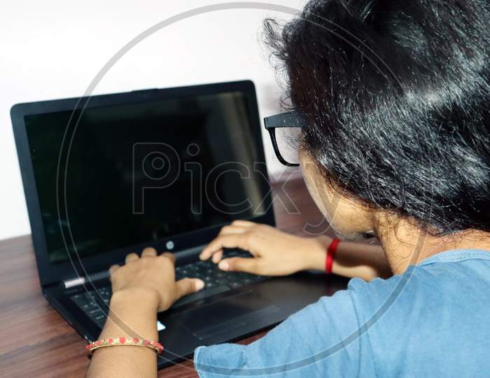 A Girl Working On Laptop From Home Backside View