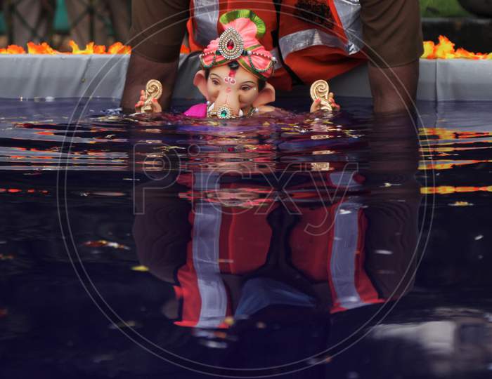 A man immerses an idol of the Hindu god Ganesh, the deity of prosperity, in an artificial pond during the Ganesh Chaturthi festival in Mumbai, India, August 23, 2020.