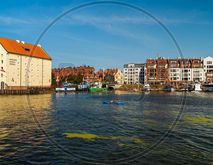 Gdansk, North Poland - August 13, 2020: People Riding Kayak Enjoying Summer In Motlawa River Adjacent To Polish Architecture Near Baltic Sea During Covid 19 Pandemic