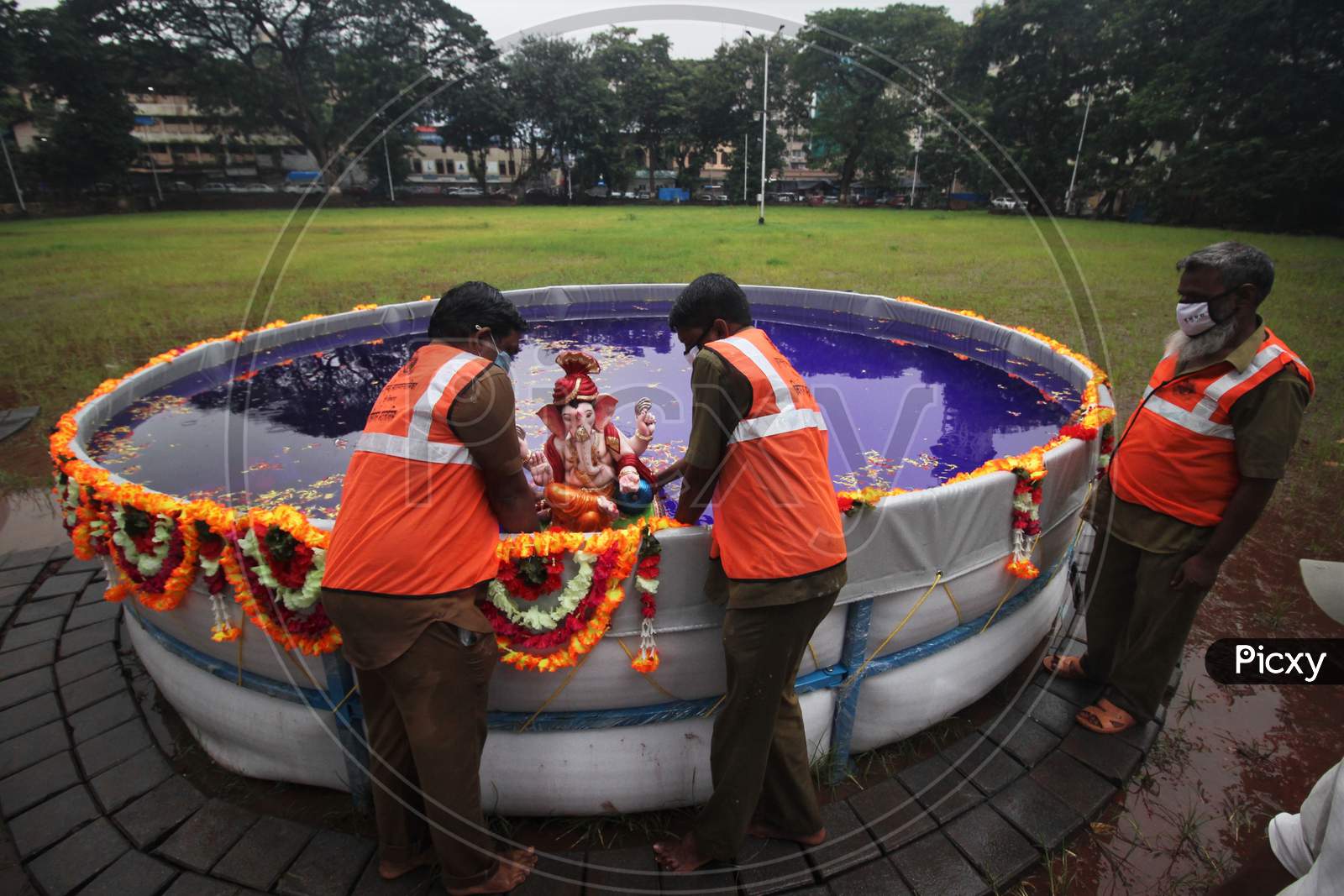 Bmc people immerses an idol of the Hindu god Ganesh, the deity of prosperity, in an artificial pond during the Ganesh Chaturthi festival in Mumbai, India, August 23, 2020.