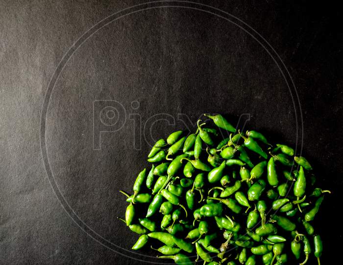 Many Small Green Chillies Isolated On Black Background. Copy Space.