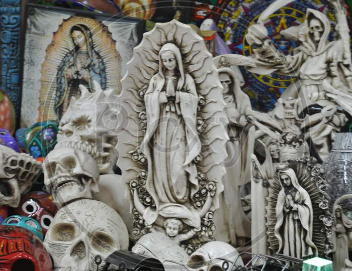 Statue Of The Virgin Mary Along With Skull And Other Carvings In A Souvenir Shop In Mexico