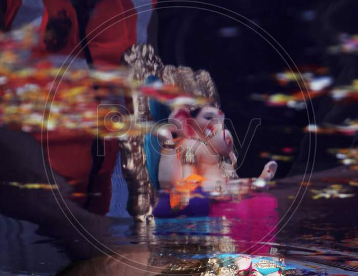 Reflection of a man immersing an idol of the Hindu god Ganesh, the deity of prosperity, is seen in an artificial pond during the Ganesh Chaturthi festival in Mumbai, India, August 23, 2020.