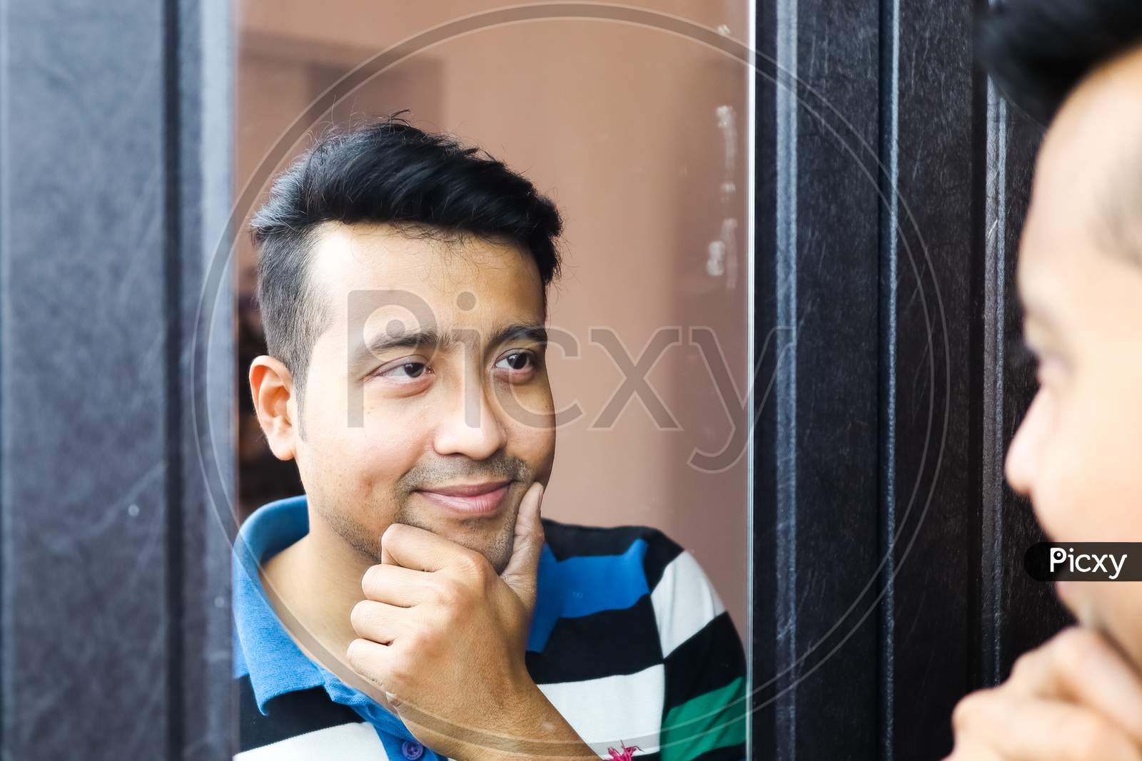 A Confident Man Looking At His Reflection In Mirror And Making Smile Gesture