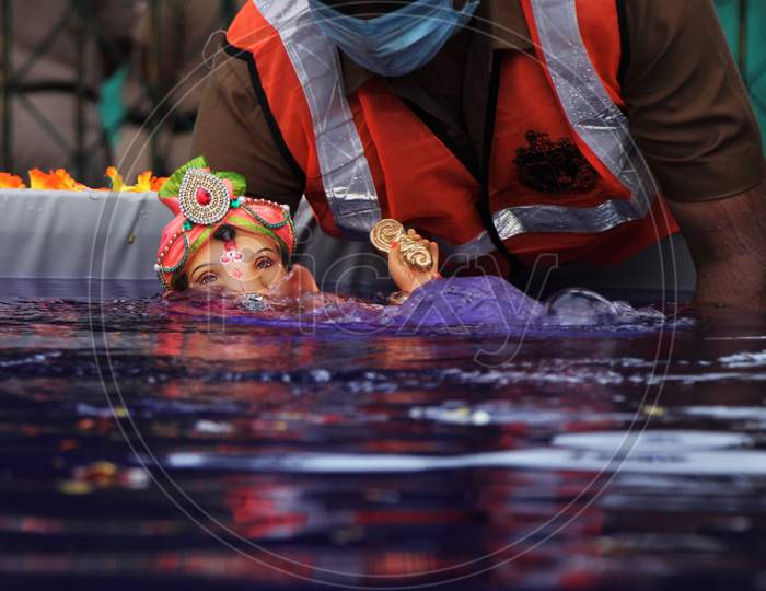 A man immerses an idol of the Hindu god Ganesh, the deity of prosperity, in an artificial pond during the Ganesh Chaturthi festival in Mumbai, India, August 23, 2020.
