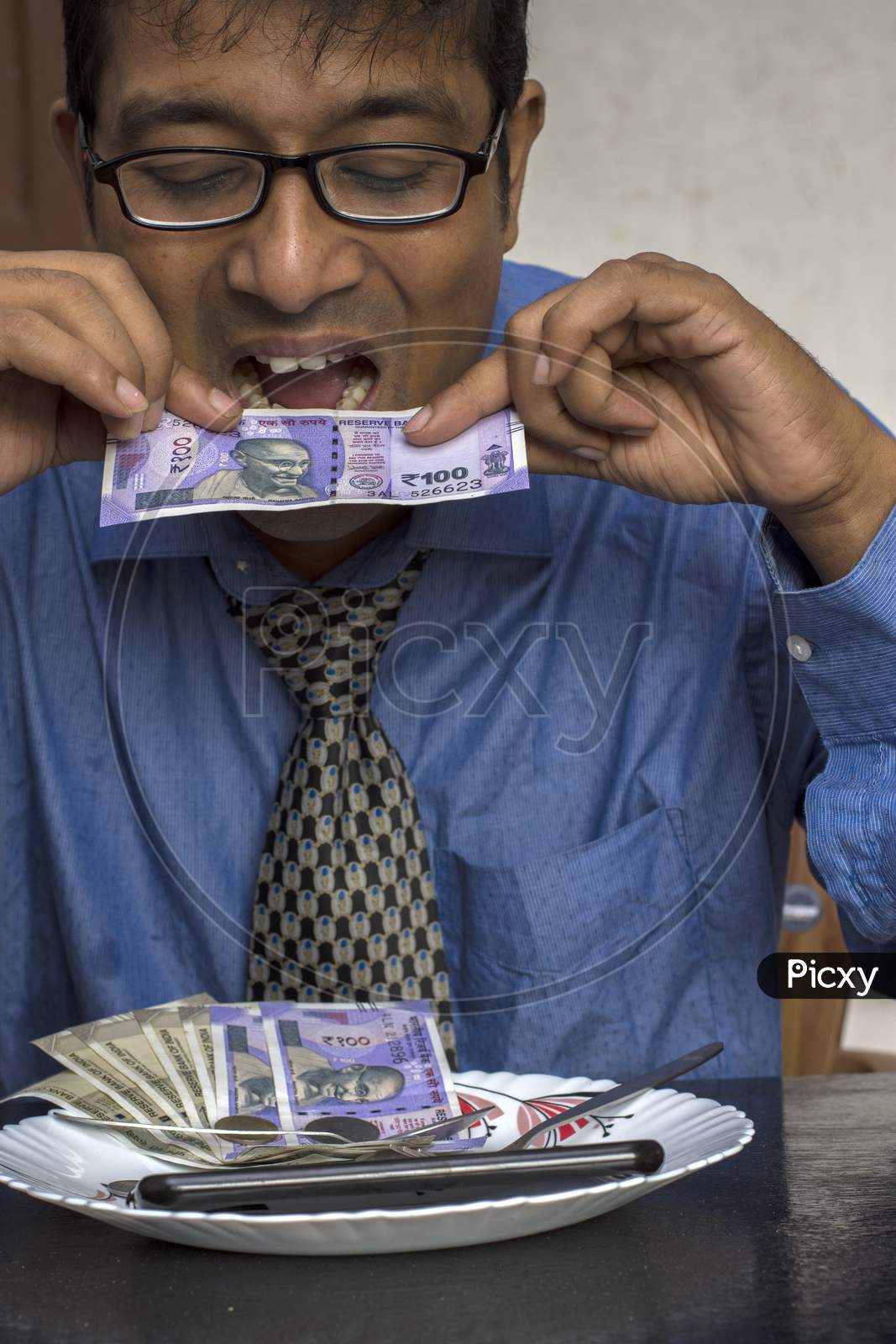 Greedy Businessman Eating Indian Note From A Dish With Some Coins.