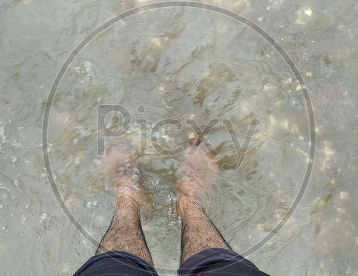 24 august 2020 india; A man is standing in the river's water enjoying the cold water