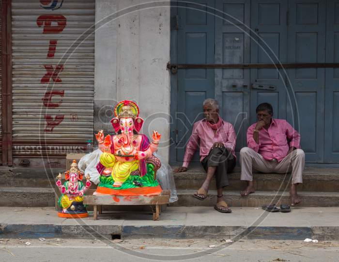 A Ganesha idol and the sellers seen relaxing at Mysuru/Karnataka/India.