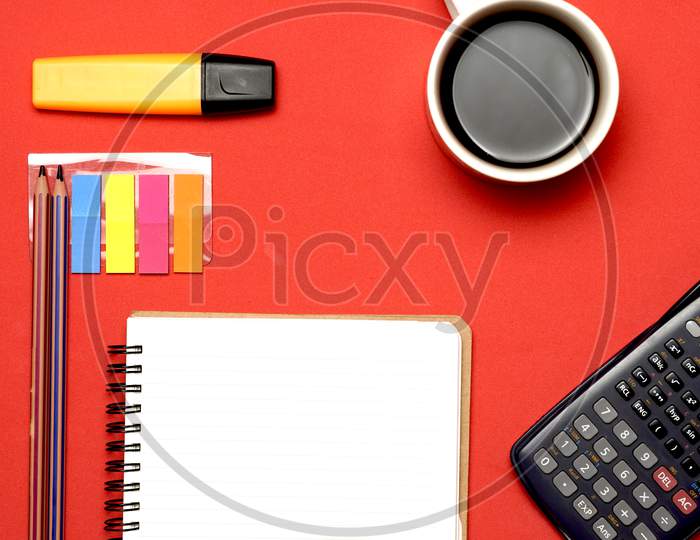 Work Space With Notebook, Stickers,Calculator Marker And Coffee On Red Background. Flat Lay. Flat Design