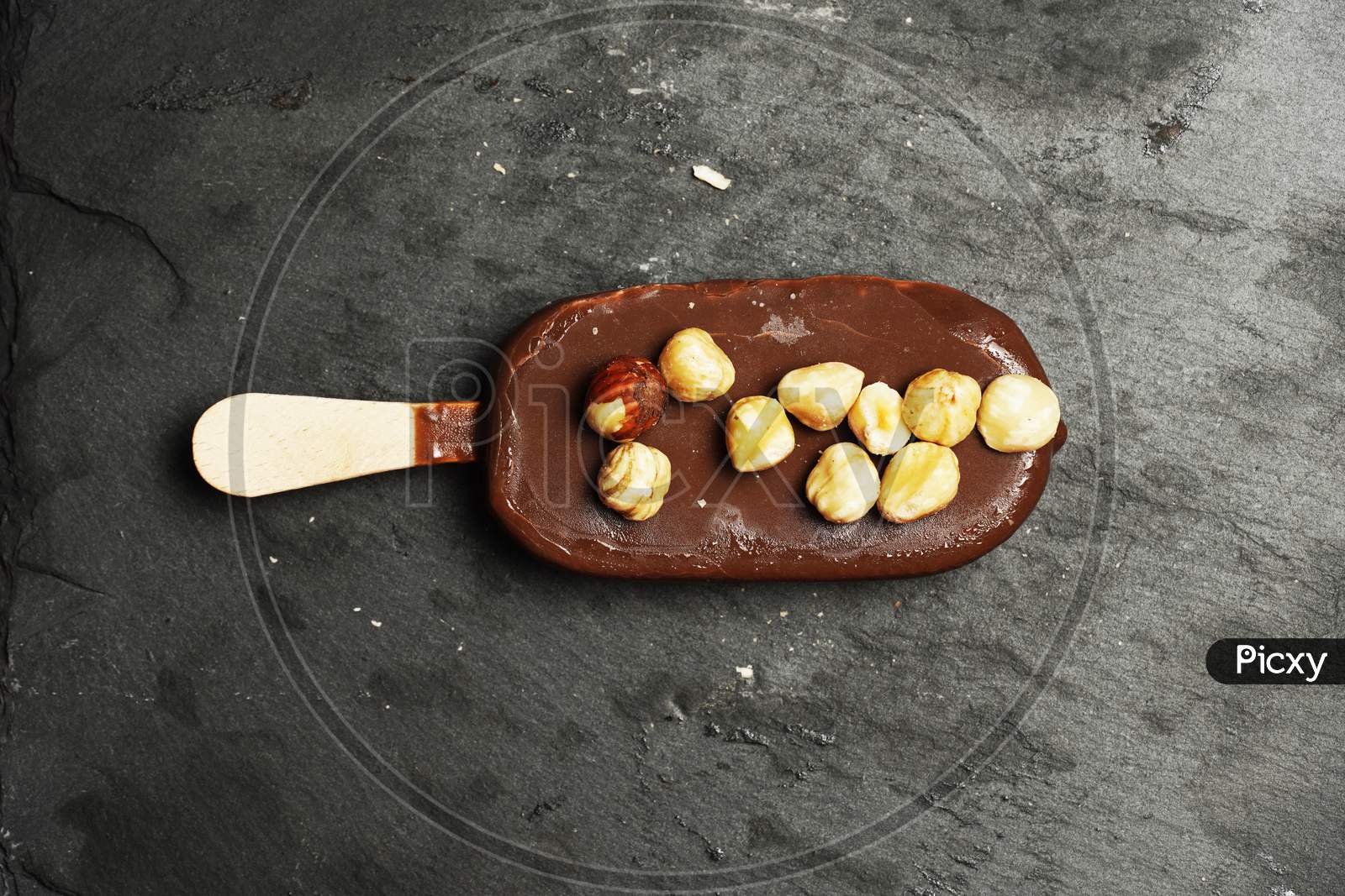 Chocolate Ice Cream With Hazelnuts On Top On A Black Slate Background. Dessert. Flat Lay Flat Design