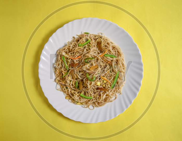Vegetarian Schezwan Noodles Or Vegetable Hakka Noodles Or Chow Mein In White Plate At Wooden Background. Schezwan Noodles Is Indo-Chinese Cuisine Hot Dish With Udon Noodles, Vegetables And Chilli Sauce