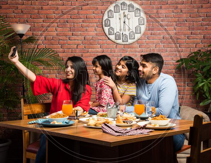 Indian Family Eating Food At Dining Table - Includes South Asian Mother, Father And Two Daughters