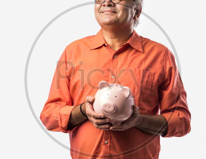 Indian Old Man Or Retired Senior Male Adult Holding Piggy Bank Or Money Box