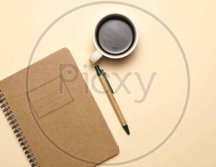 Workspace With Coffee Notebook And Pen On A Pale Orange Background. Flat Lay.