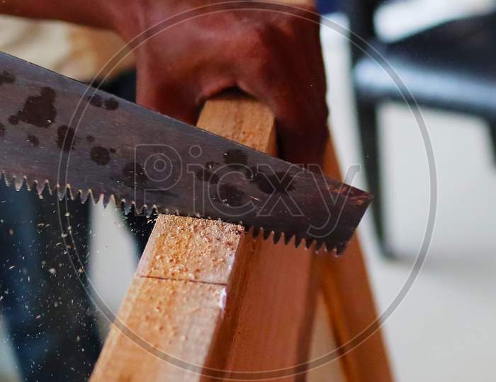 An Wooden Door Being Cut By A Saw Manually