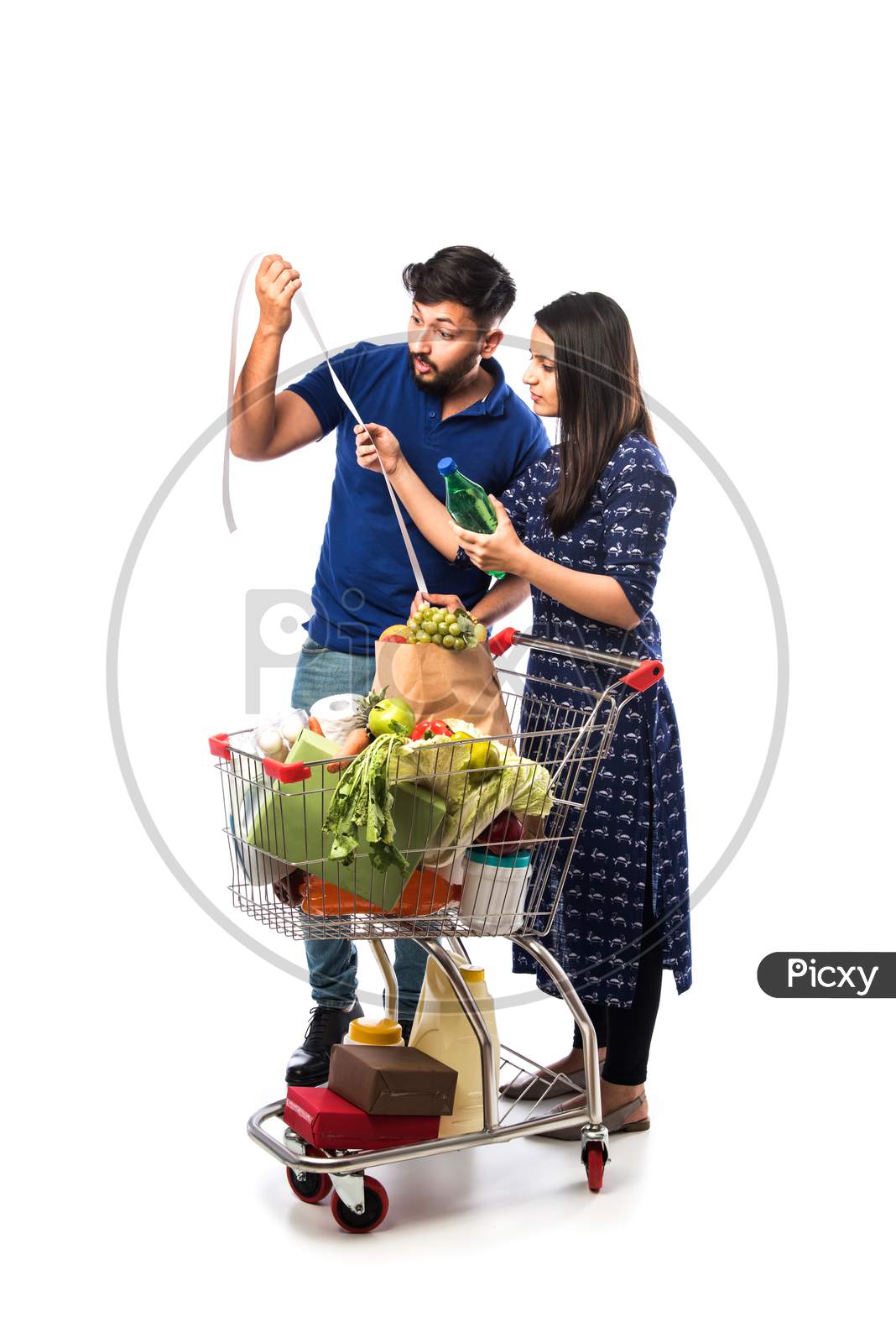 Happy Indian Couple With A Shopping Cart. Isolated Over White Background