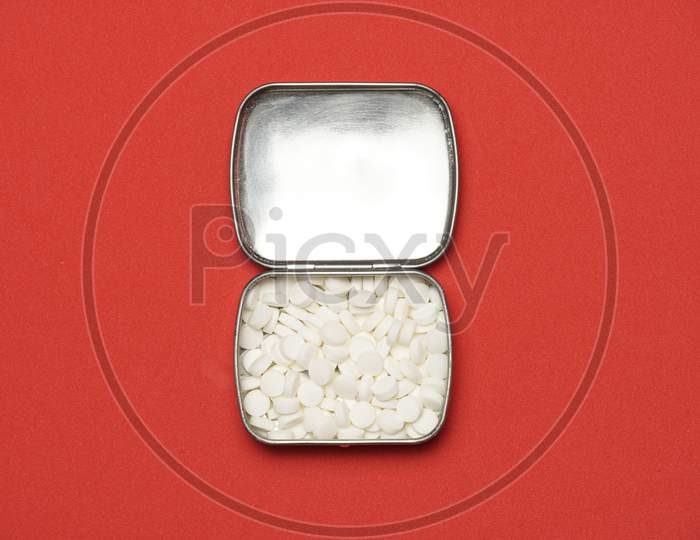 Metal Pillbox On Red Background With Space For Copy. Flat Lay.