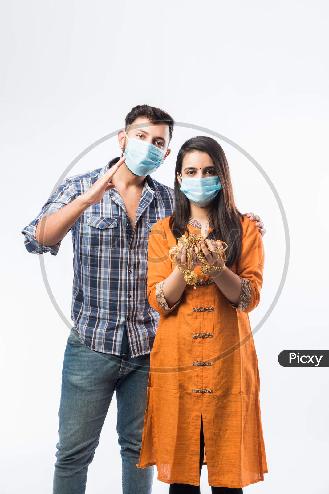 Indian Young Couple Wearing Face Mask And Holding Gold Jewelry Or Ornaments In Hand