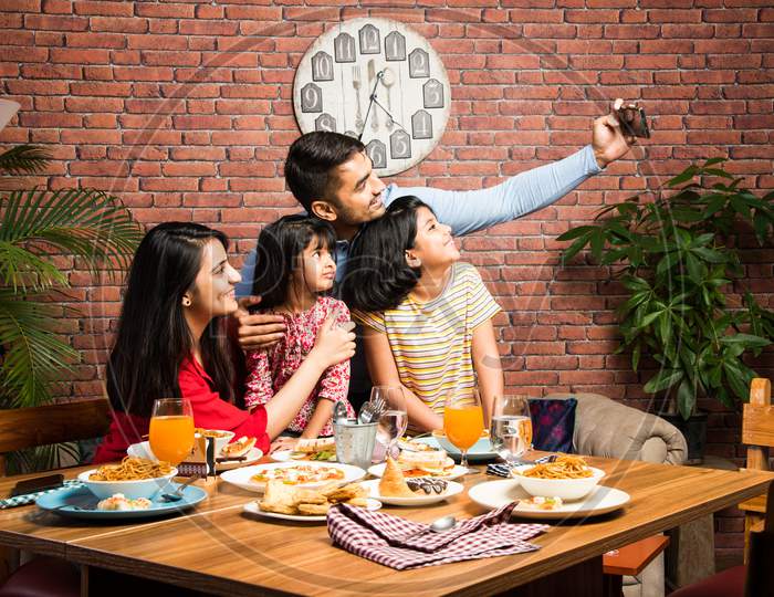 Indian Family Eating Food At Dining Table - Includes South Asian Mother, Father And Two Daughters