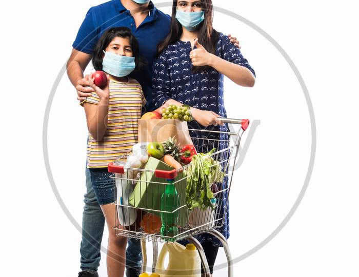 Indian Young Family Shopping Using Cart In Corona Or Covid-19 Pandemic Outbreak Wearing Mask