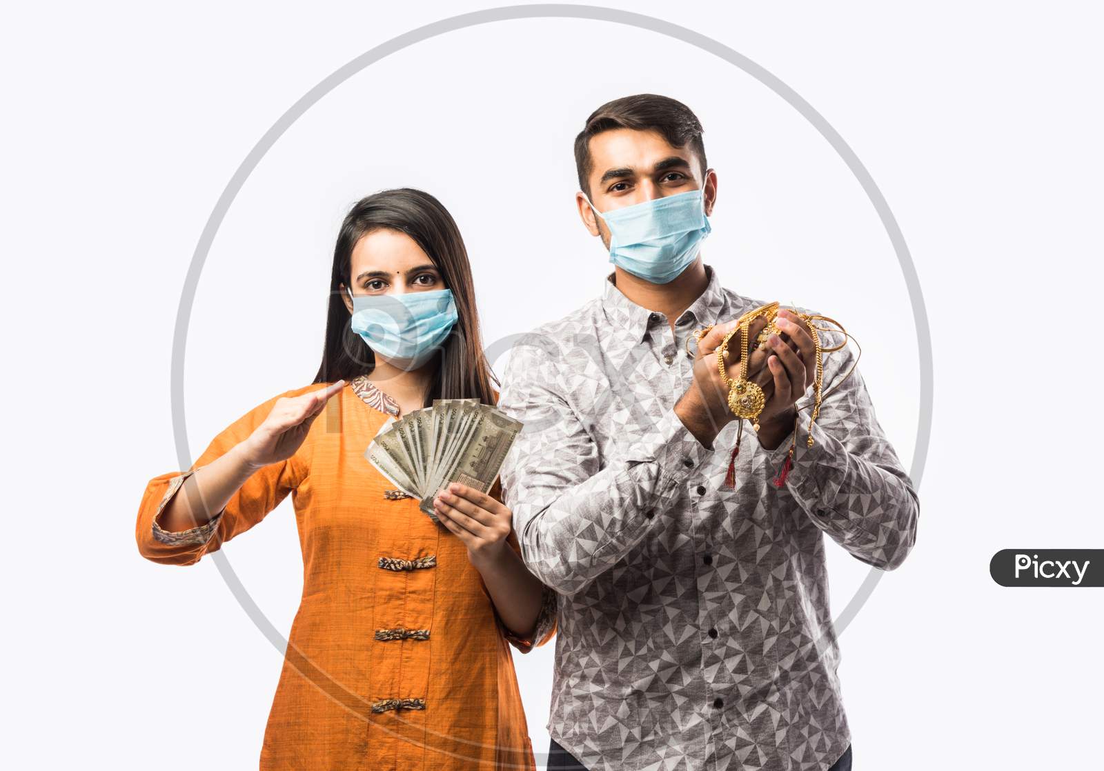 Indian Young Couple Wearing Face Mask And Holding Gold Jewelry Or Ornaments In Hand