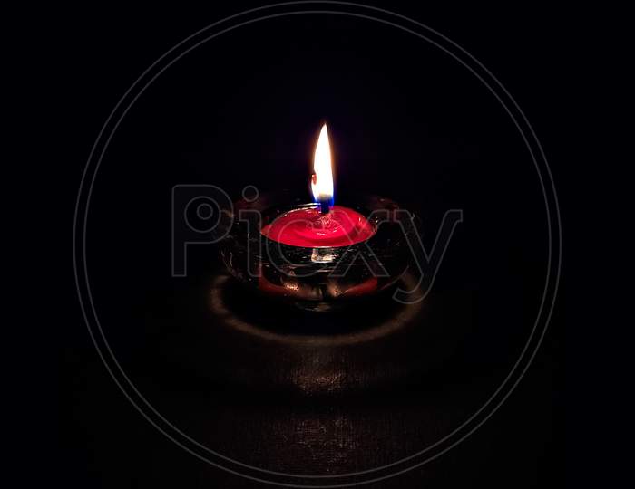 Isolated ,Closeup Image Of Small Red Colored Wax Lamp(Diya) Burning In Dark.