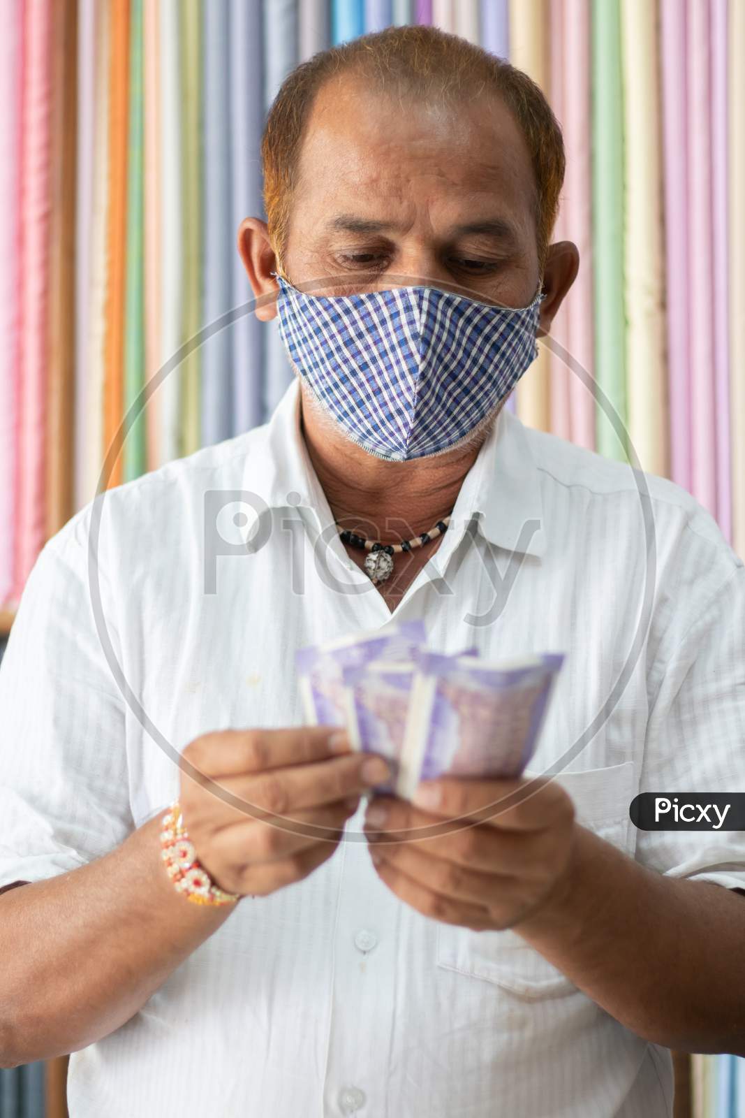 Small Business Owner In Medical Mask Counting Money At Cloth Shop During Coronavirus Or Covid-19 Crisis - Concept Of Back To Business, Making Money And Reopen Economy
