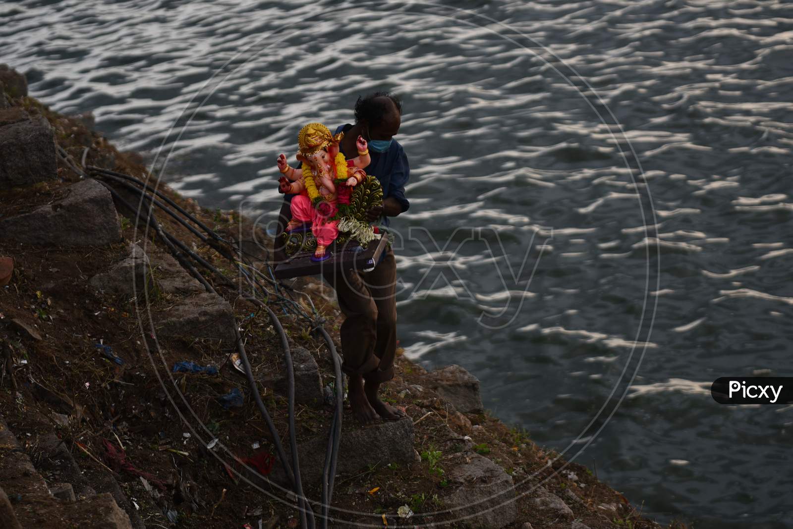 A GHMC worker with a facemask carries the idol of Hindu deity, Lord Ganesh to immerse in Hussain Sagar on August 25, 2020
