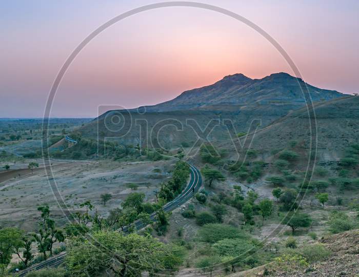 Rising Sun Behind The Hills Along With A Railway Line In A Village , Pune.