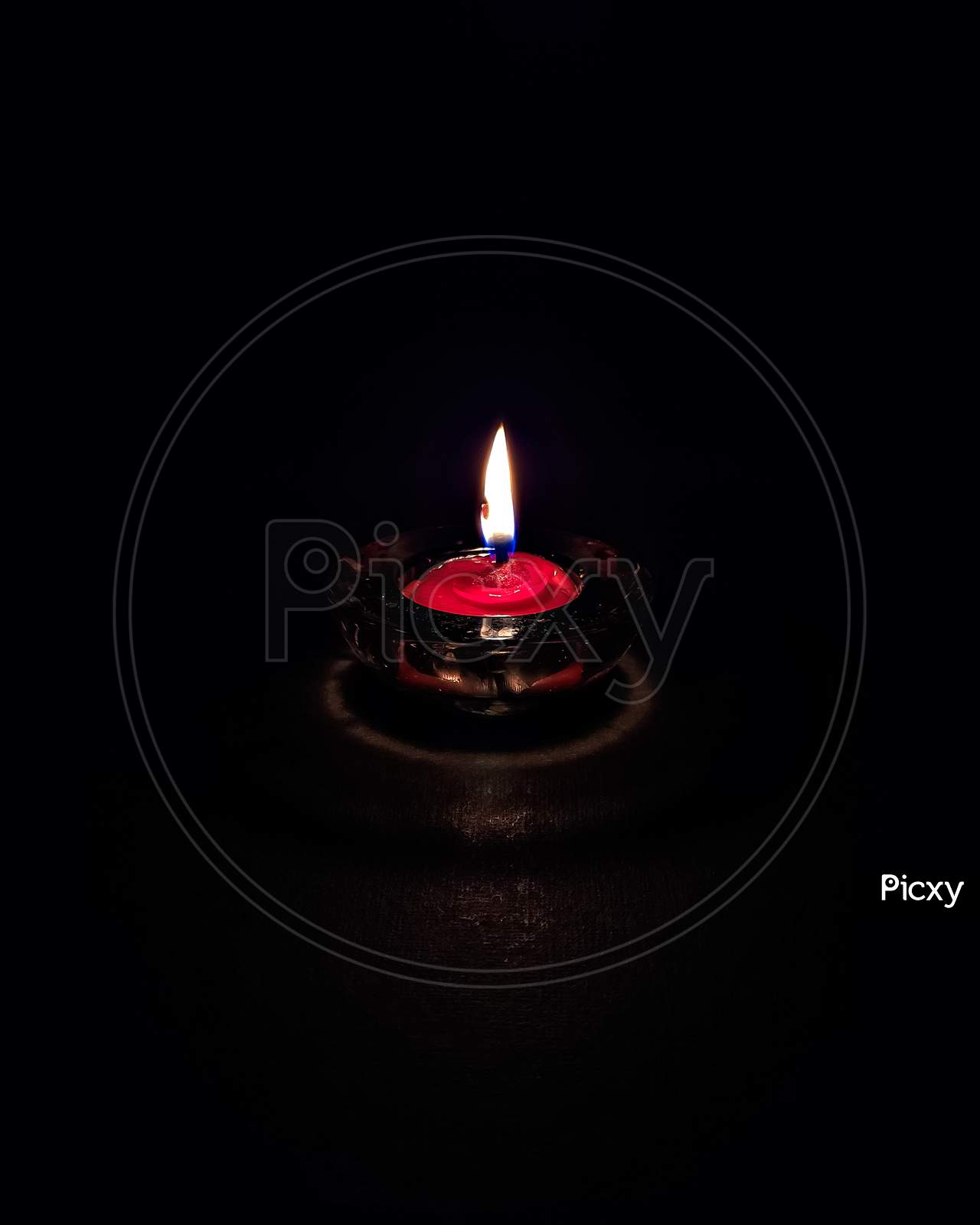 Isolated ,Closeup Image Of Small Red Colored Wax Lamp(Diya) Burning In Dark.