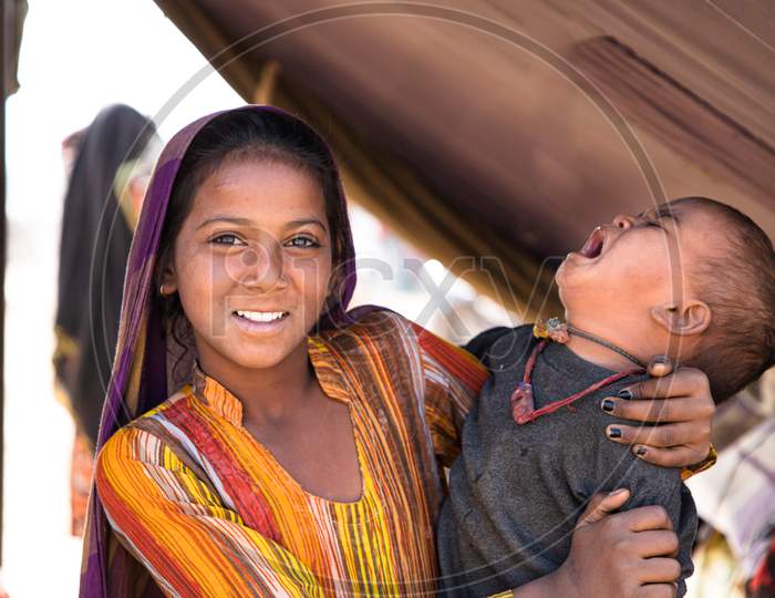 Indian young girl in colorful Rajasthani dress posing with his brother in the Pushkar Camel Mela