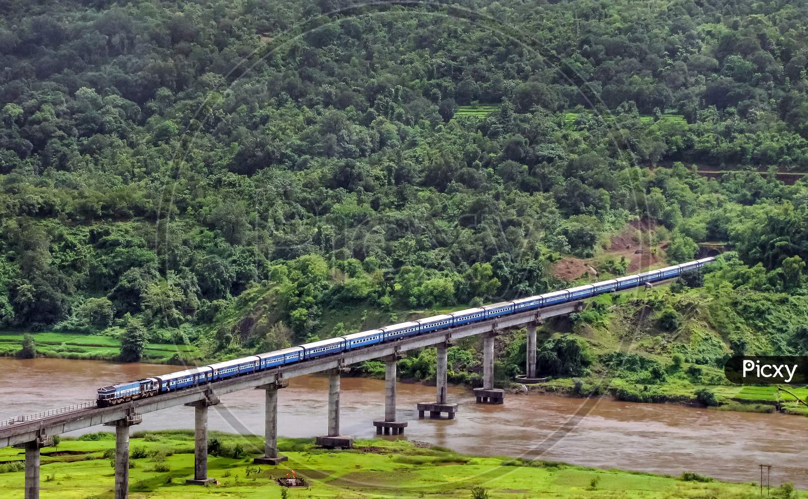Scenic View Of A Train Exiting Tunnel And Crossing Bridge.