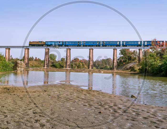 Narrow Gauge Train Crossing Marhu River Bridge With River.