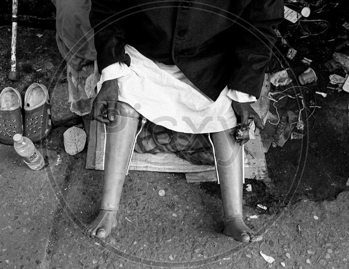 Homeless Indian senior handicapped or disabled man sitting somewhere on a street of vrindavan