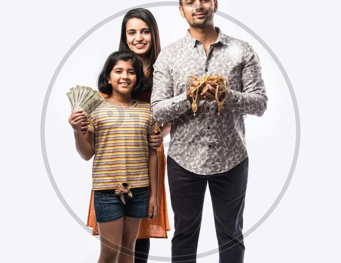 Indian couple with cute daughter holding gold jewelry, ornaments - Asset or Gold Loan concept