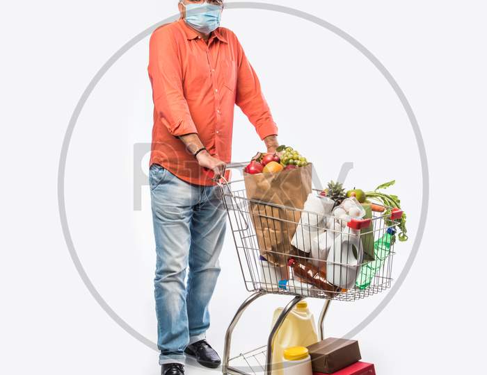 Indian Asian Senior Man Wears Face Mask While Pushing Shopping Trolly Or Cart