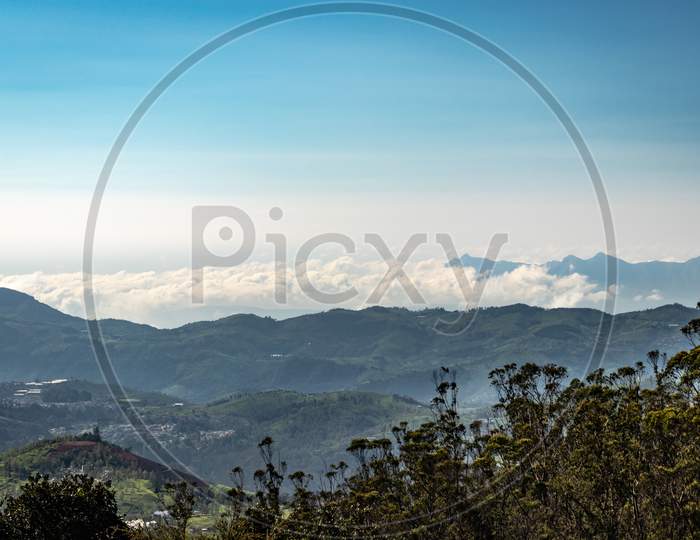 Mountain Range With Cloud Layers And Green Forest