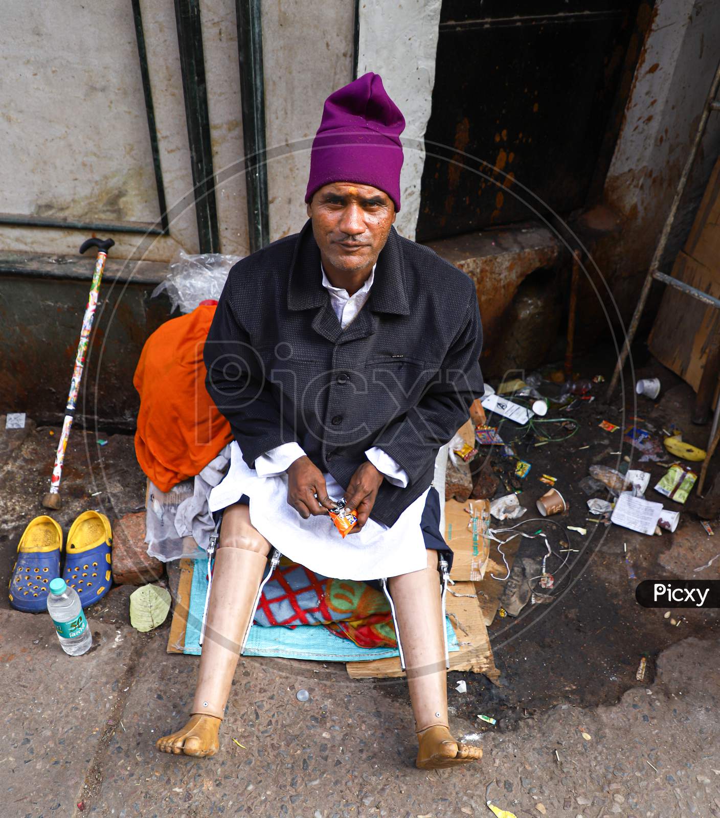 Homeless Indian senior handicapped or disabled man sitting somewhere on a street of vrindavan